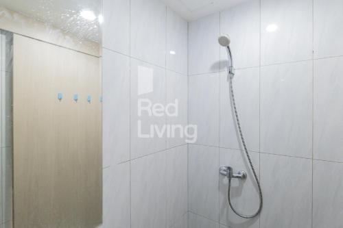 uma casa de banho com um chuveiro e uma placa de estar vermelha na parede em RedLiving Apartemen Jakarta Living Star - BoboRooms em Jakarta
