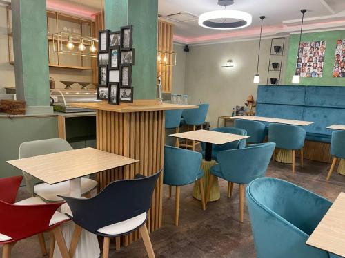 un ristorante con tavoli in legno e sedie blu di Design- und Kunsthotel München a Monaco