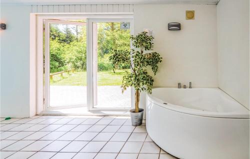 La salle de bains est pourvue d'une baignoire et d'une plante en pot. dans l'établissement 8 Bedroom Nice Home In ster Assels, à Sillerslev