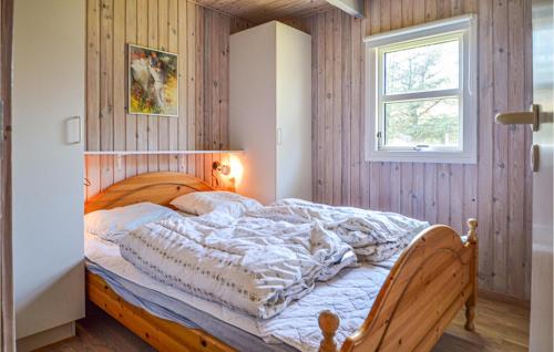 1 cama en un dormitorio con pared de madera en Awesome Home In Blokhus With Wifi, en Blokhus