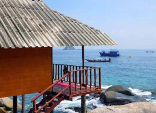 a bench under an umbrella on the beach at OK2 Mamajim Bungalows in Koh Tao