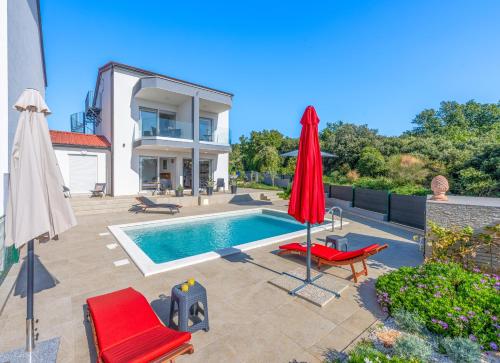 a swimming pool with a red umbrella and chairs and a house at Villa Rozeta in Marčana