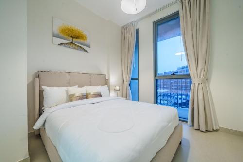 a bedroom with a white bed and a large window at Dar Alsalam - Modern Apartment With Stunning Views in Dania 3 in Dubai