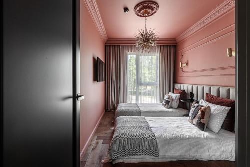 2 Betten in einem Zimmer mit rosa Wänden und einem Fenster in der Unterkunft Hill Garden Residence & SPA in Palanga
