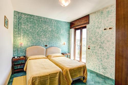 2 camas en una habitación con papel pintado verde en Grand Hotel Hermitage, en SantʼAgata sui Due Golfi