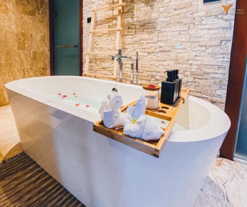 a bath tub with towels on a wooden tray in a bathroom at Yotaka Khanom in Ban Phang Phrao