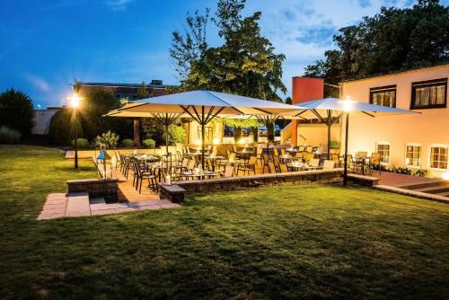 a patio with tables and chairs and umbrellas at Hotel Vorfelder in Walldorf