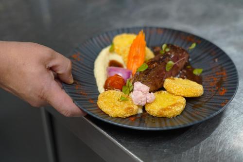 a person holding a blue plate with food on it at Best Western l'Atelier 117 in Maubeuge
