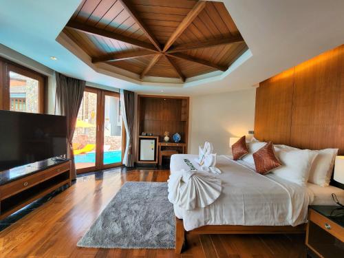 a bedroom with a large bed and a flat screen tv at Yotaka Khanom in Ban Phang Phrao