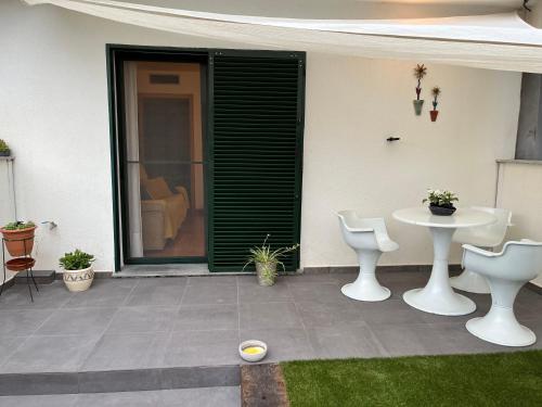un patio con 2 sillas blancas y una mesa en La Caseta de Beli, en La Galera