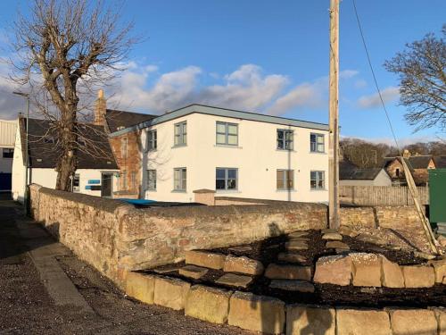 a stone wall in front of a white house at The old post office in Golspie