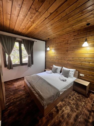 a bedroom with a large bed in a wooden wall at Райски кът “Еленова поляна” in Dobărsko