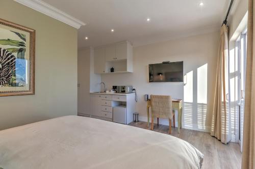 a bedroom with a large bed and a kitchen at Thyme Wellness Spa and Guesthouse in Cape Town