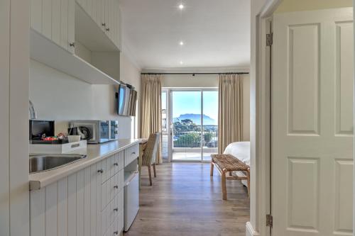 eine Küche mit einem Waschbecken und einer Tür mit Aussicht in der Unterkunft Thyme Wellness Spa and Guesthouse in Kapstadt