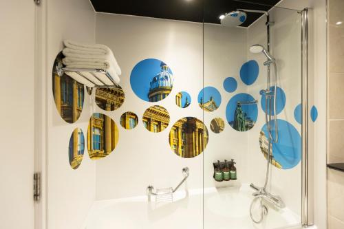 a bathroom with a shower with blue and yellow stickers on the wall at Crowne Plaza Birmingham NEC by IHG in Bickenhill