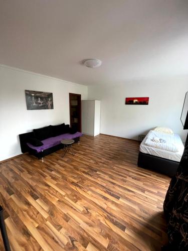 a living room with a bed and a wooden floor at Studio Apartment mit Balkon in Neumünster