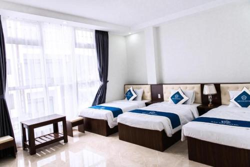 a bedroom with two beds and a large window at Bảo Sơn Hotel in Ha Long