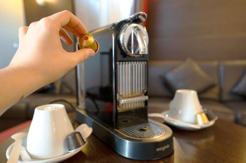 a person is using a coffee maker on a table at Best Western l'Atelier 117 in Maubeuge