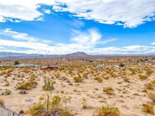 a view of the desert with a house in the distance at KAMPINK! Pool, Spa, Gameroom Compound with Amazing Views on 2.5 Acres in Joshua Tree