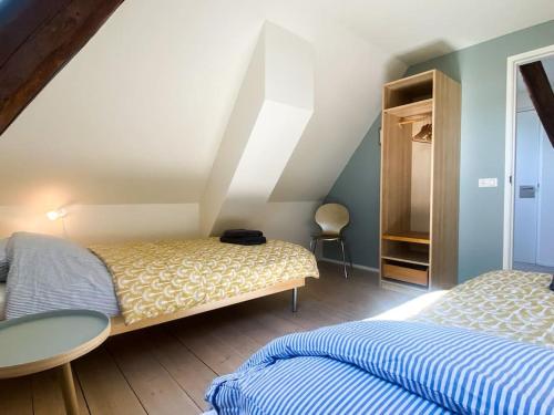 a bedroom with two beds and a table and a chair at Wadhuis met spectaculair uitzicht op zee! in Nes