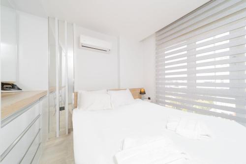 a white bedroom with a bed and a window at Residence w Shared Pool 3 min to Mall of Antalya in Antalya