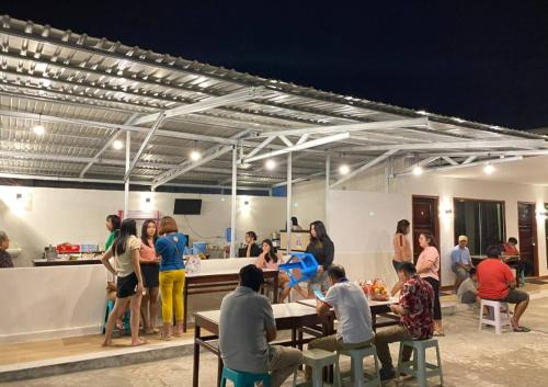 um grupo de pessoas em pé em torno de uma cozinha em um quarto em Amadeo Guest House em Ratodena