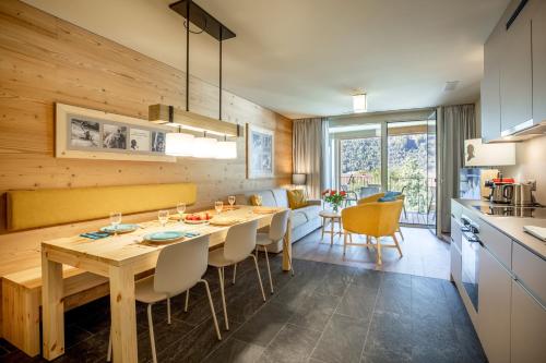 a kitchen and dining room with a wooden table and chairs at SWISSPEAK Resorts Meiringen in Meiringen