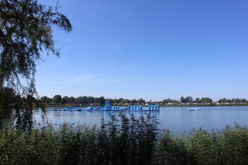 a lake with a blue dock in the middle of it at Ferienhaus Strandnah - Wohnung 1 in Otterndorf