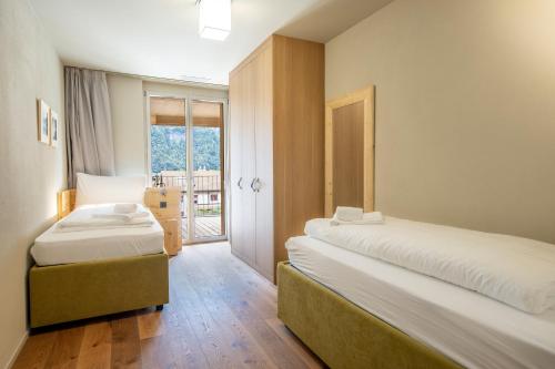 two beds in a room with a window at SWISSPEAK Resorts Meiringen in Meiringen