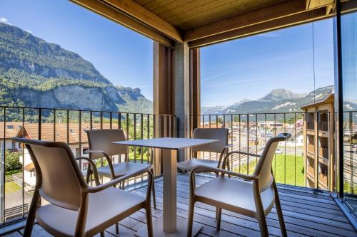 a table and chairs on a balcony with a view of mountains at SWISSPEAK Resorts Meiringen in Meiringen