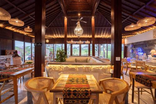 ウブドにあるBarong Bali Resort Ubudのテーブルと椅子、ソファ付きのレストラン