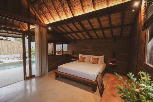 a bedroom with a bed in a room with a pool at Kalyana Villa Gili Air in Gili Islands