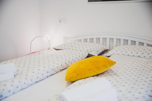 a white bed with two pillows and a yellow pillow at Gotar Apartment with Garden in Kobarid