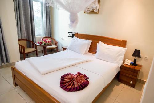 a bedroom with a large bed with a flower on it at Olympic Hotel in Kigali