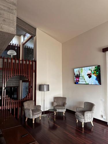 a living room with two chairs and a tv on the wall at Villa Belvedere di Popiglio in Popiglio