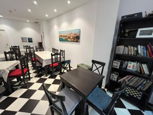 a restaurant with tables and chairs and a book shelf at Hostel A2C in Seville