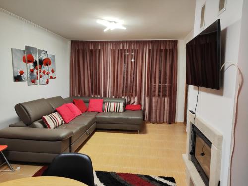 een woonkamer met een bank en een televisie bij Апартамент "Red&Black" в Гранд Манастира - Пампорово in Pamporovo