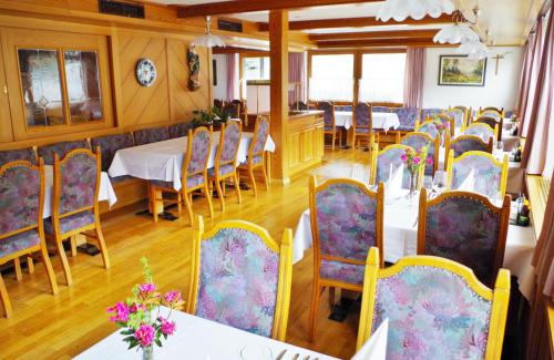 a dining room with tables and chairs with flowers on them at Hotel Edi in Samnaun