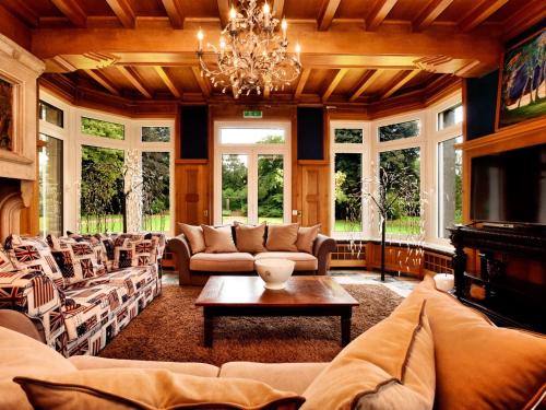 a living room with couches and a chandelier at Luxurious castle with hot tub in the Belgian in Jamoigne