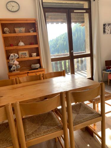 une salle à manger avec une table et des chaises et une fenêtre dans l'établissement Pra Chauvet - Appartement 5 personnes Praloup, à Uvernet