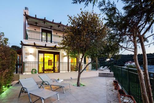 a house with a patio and chairs in front of it at Your Private Luxury Villa, Pool, Sea view, Rethymno in Kiriánna