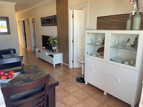 een woonkamer met een witte kast en een tafel bij Residencial La Mar mit Meerblick in Puerto de Santiago