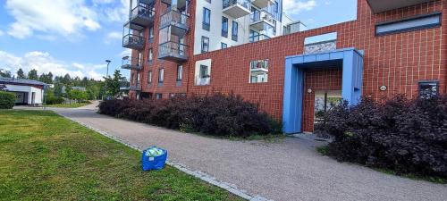 a building with a blue trashcan sitting in the grass at Aurora Home Kivistö 1-bedroom apartment for up to 8 near Helsinki Vantaa Airport and Helsinki city center in Vantaa