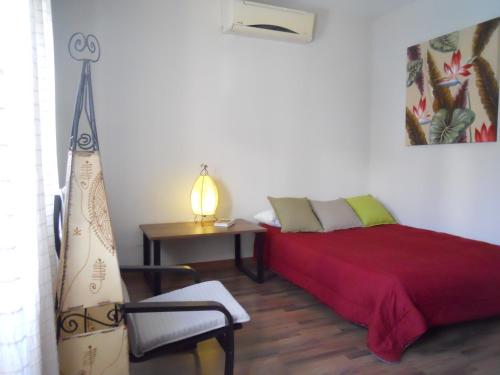 um quarto com uma cama vermelha, uma mesa e um candeeiro em Naturalia: La casita con Patio em Cáceres