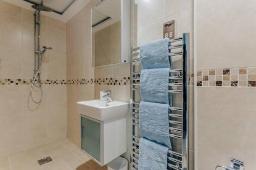 a bathroom with a sink and a shower with blue towels at Lovely One Bedroom Flat in Bournemouth