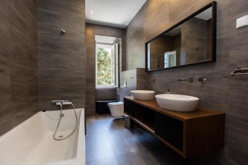 ein Badezimmer mit zwei Waschbecken, einer Badewanne und einem Spiegel in der Unterkunft Apartments of the Marques in Lissabon