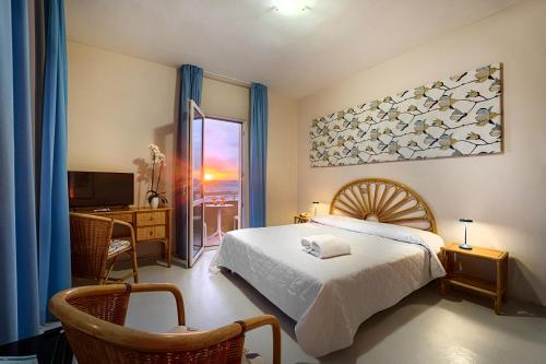 a bedroom with a bed and a desk and a window at Hotel Mida in Scoglitti