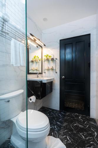 a bathroom with a toilet and a sink and a black door at Luangprabang D'or Boutique Hotel in Luang Prabang