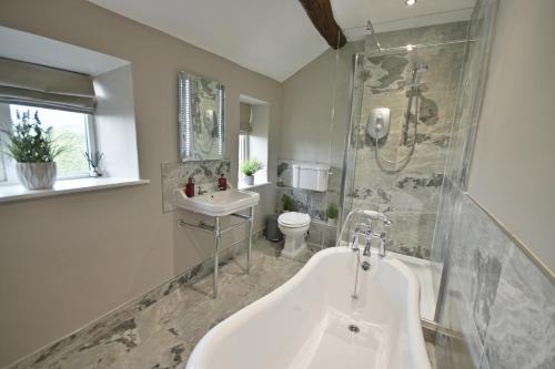 a bathroom with a tub and a toilet and a sink at Pendle Hill Farm - 5* Luxury, Log fire, Parking in Burnley