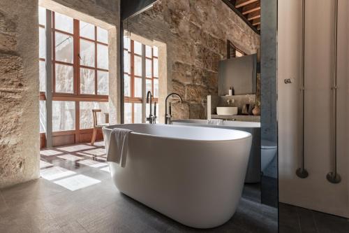 a white bath tub in a bathroom with a sink at Nobis Hotel Palma, a Member of Design Hotels in Palma de Mallorca